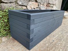 a large wooden planter sitting next to a stone wall