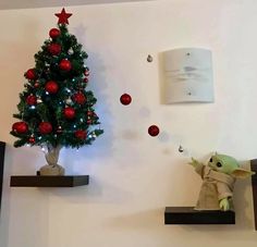 two shelves with christmas decorations and a star wars yoda tree on one shelf, and a red ornament hanging from the wall