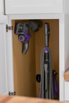 a close up of a purple vacuum in a cabinet with other items on the shelf