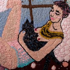 a close up of a woman with a cat in her lap on a quilted surface