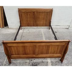 a wooden bed frame sitting on top of a cement floor