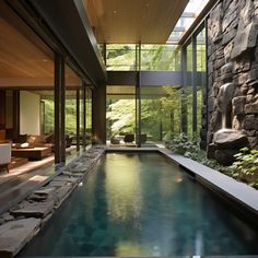 an indoor swimming pool in the middle of a room with stone walls and floor to ceiling windows