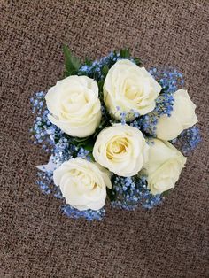 a bouquet of white roses and baby's breath on a brown carpeted surface