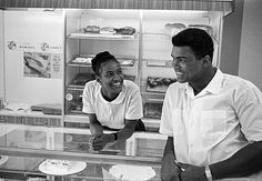 a man and woman standing in front of a display case with pastries on it