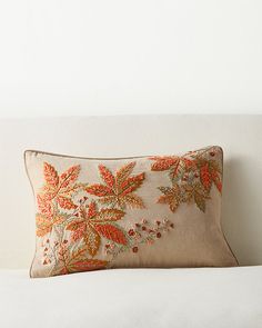 an embroidered pillow sitting on top of a white couch