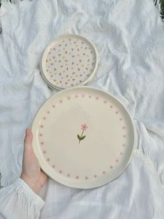 two white plates with pink flowers and stars on them, one being held by a hand