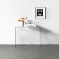 a vase with flowers sitting on top of a white table next to a framed photo