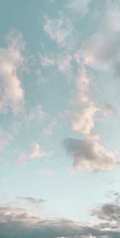 the airplane is flying high in the sky with some clouds above it and another plane on the ground below