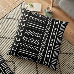 a black and white floor pillow sitting on top of a rug next to a chair