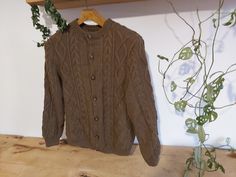 a brown sweater hanging on a wooden shelf