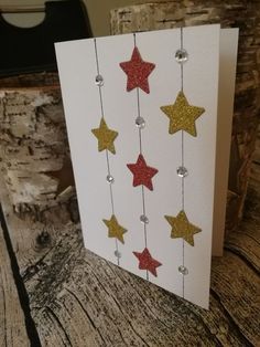 a card with gold and red stars hanging from it's side on a wooden table