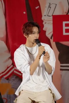 a young man holding a microphone in his right hand and wearing khaki pants