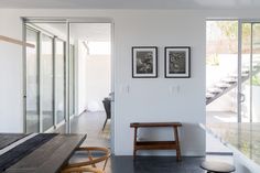 an empty room with two framed pictures on the wall and a bench in front of it