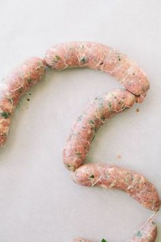 an uncooked sausage is laying on a white surface next to some parsley