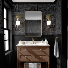 a bathroom with black walls and white counter tops, gold accents on the mirror above the sink