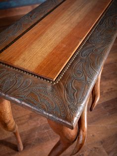 a wooden table with intricate carvings on the top and bottom, sitting on a hard wood floor