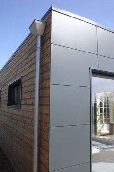 the side of a house that is made out of wood and metal, with a light pole next to it