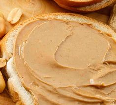 peanut butter spread on bread with peanuts around it