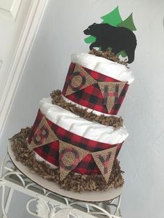 a three tiered cake decorated with red and black plaid fabric, topped with a bear