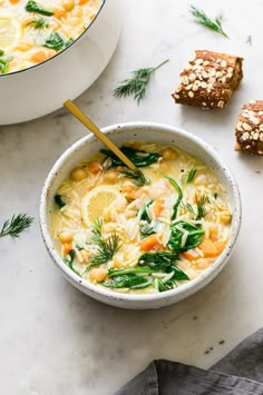 a white bowl filled with soup next to two pieces of bread on top of a table