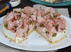 a white plate topped with a cut in half cake covered in ham and pistachio