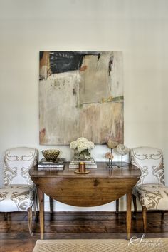 a table with two chairs and a painting on the wall