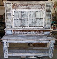 an old wooden bench sitting inside of a garage next to a wall with windows on it