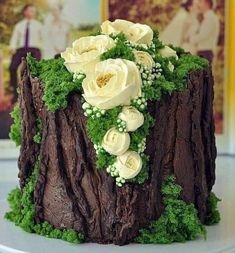 there is a cake made to look like a tree stump with flowers on it and moss