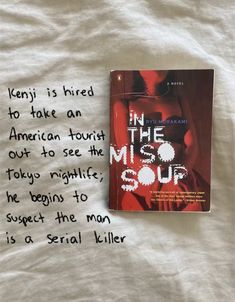 the book in the miso sour is laying on top of a white bed sheet