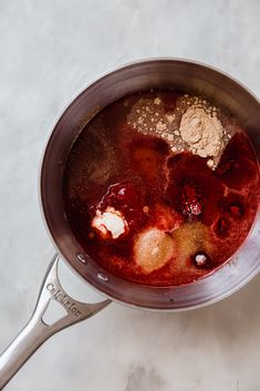 a pot filled with liquid sitting on top of a white counter next to a spoon