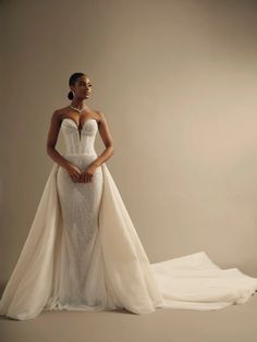 a woman in a wedding dress standing on a white surface with her hands on her hips