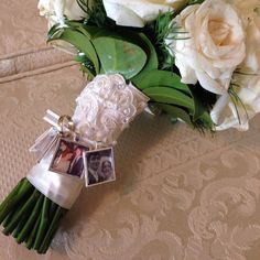 a bouquet of white roses sitting on top of a bed next to a couple's photo