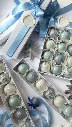 an assortment of blue and white christmas ornaments in a gift box with ribbon around them