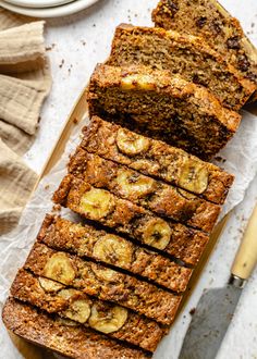 sliced banana bread sitting on top of a cutting board next to a knife and fork