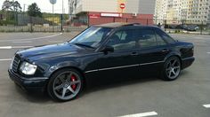 a black mercedes benz is parked in a parking lot