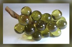 a bunch of green grapes sitting on top of a white table next to a wooden stick