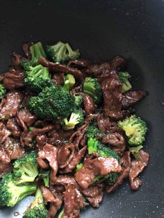 beef and broccoli stir fry in a wok with brown sauce on top