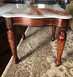 a marble top coffee table with wooden legs in a living room or dining room area