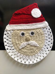 a crocheted santa clause hat with eyes and a mustache on it's face