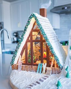 a gingerbread house is decorated with icing and snow on the roof for christmas