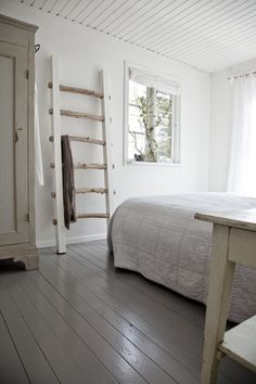 a bed sitting in a bedroom next to a wooden dresser and window on top of a hard wood floor