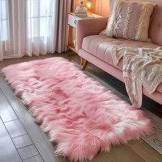 a living room with a pink couch and rug on the floor next to a window