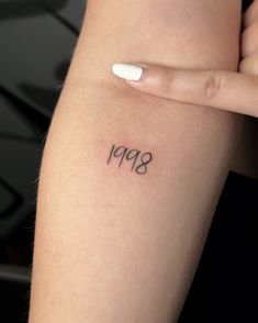 a woman's arm with the number 999 tattooed on her left side, in black ink