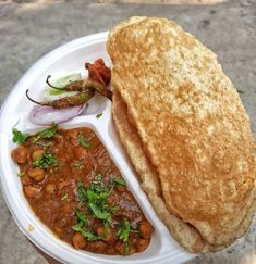 a person holding a white plate with food on it and a sandwich in the middle