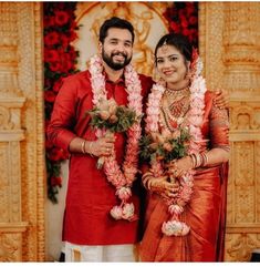 two people standing next to each other in front of flowers