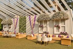 an outdoor wedding venue set up with purple and white decor on the walls, tables and chairs