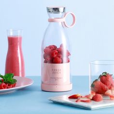 a glass bottle filled with strawberries next to a plate of fruit