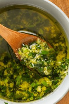 a wooden spoon in a bowl filled with broccoli and other green food items