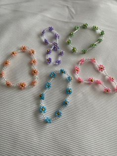 four different colored beads on a white sheet with one beaded necklace and the other is made out of glass beads