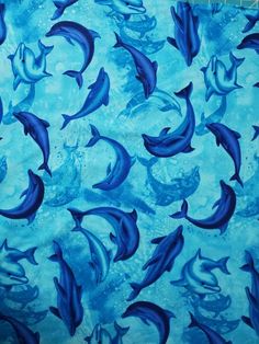 a group of dolphins swimming in the ocean on a blue watercolored background with bubbles